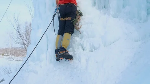 Alpinist man with ice tools axe climbing a large wall of ice. Stock-Footage 128565868