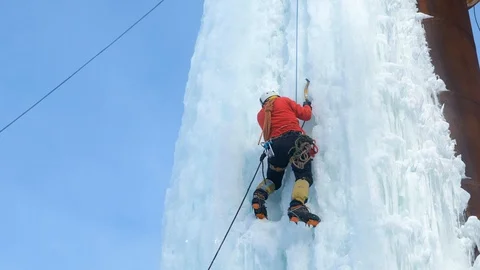 Alpinist man with ice tools axe climbing a large wall of ice. Stock-Footage 128565963