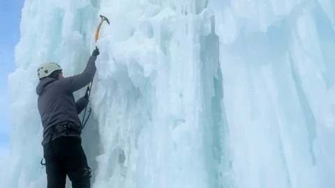 Alpinist man with ice tools axe climbing a large wall of ice Stock-Footage 128566058