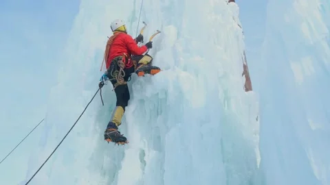 Alpinist man with ice tools axe climbing a large wall of ice. Stock-Footage 135707281