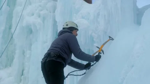Alpinist man with ice tools axe climbing a large wall of ice. Stock-Footage 135707358