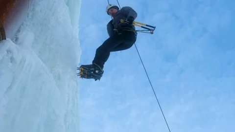 Alpinist man with ice tools axe climbing large wall of ice. going down in rope Stock-Footage 139290405