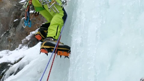 Alpinist man with ice tools axe climbing a frozen waterfall, a large wall of ice Stock Footage 143047816