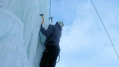 Alpinist man with ice tools axe climbing a large wall of ice. Stock Footage 145630201