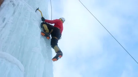Alpinist man with ice tools axe climbing a large wall of ice. Stock Footage 145630448