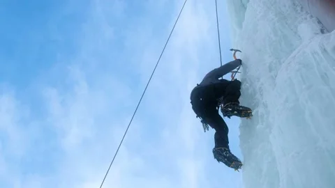 Alpinist man with ice tools axe climbing a large wall of ice. Stock Footage 145630592