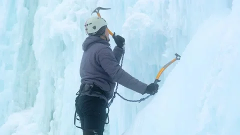 Alpinist man with ice tools axe climbing a large wall of ice. Stock Footage 146501675