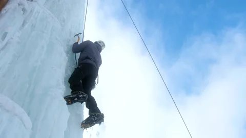 Alpinist man with ice tools axe climbing a large wall of ice. Stock Footage 146501736