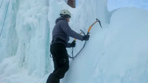 Alpinist man with ice tools axe climbing a large wall of ice. Stock Footage 148075003