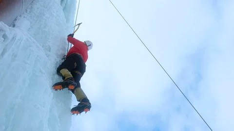 Alpinist man with ice tools axe climbing a large wall of ice. Stock Footage 148075216