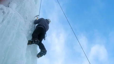 Alpinist man with ice tools axe climbing a large wall of ice. Stock Footage 148075331