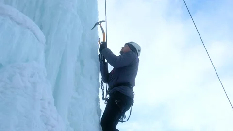 Alpinist man with ice tools axe climbing a large wall of ice. Stock Footage 155871777
