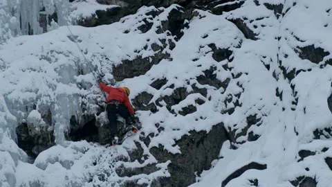 Alpinist man with ice tools axe climbing a frozen waterfall, a large wall of ice Stock Footage 160234701