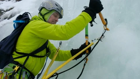 Alpinist man with ice tools axe climbing a frozen waterfall, a large wall of ice Stock Footage 164884654