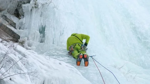 Alpinist man with ice tools axe climbing a frozen waterfall, a large wall of ice Stock Footage 166131004