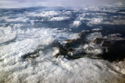 Alps mountains among the clouds view from the plane. Stock Photos