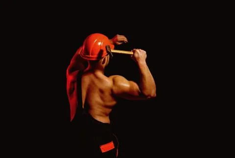 Already under construction. Construction worker hammer a nail. Muscular man Stockfoto's