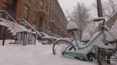 Alt snow falls on a bicycle parked on a brownstone block in Brooklyn Vidéo 147614472