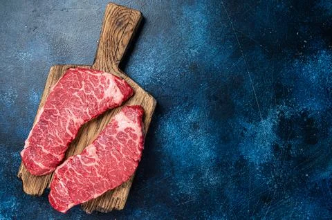 Alternative beef steak Denver, raw meat steak on a wooden board. Blue background Stock Photos