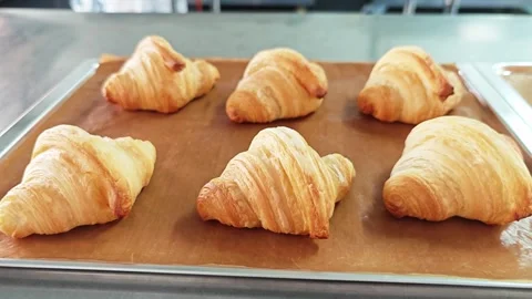 Alternative low angle view of freshly baked butter croissants on a baking sheet. Stock Footage 347633135