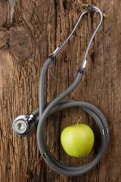 Alternative medicine - stethoscope, clipboard and green apple on wood table top Photos