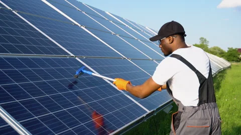 Alternative power plant worker in uniform cleaning solar panels with mop Stock Footage 246801878