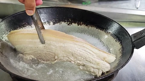Alternative view of boiling a large piece of pork belly in a metal wok. Stock Footage 346761149