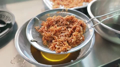 Alternative view of draining freshly fried crispy shallots over a bowl of oil. Stock Footage 346536837