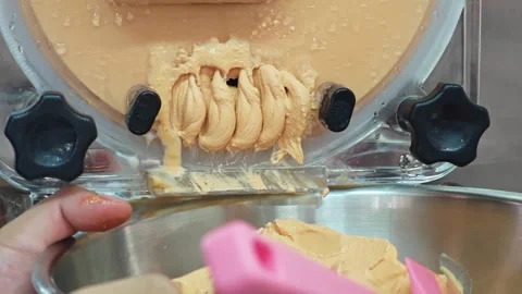 Alternative view of fresh Thai tea gelato ice cream dispensing from a machine. Stock-Footage 347632908
