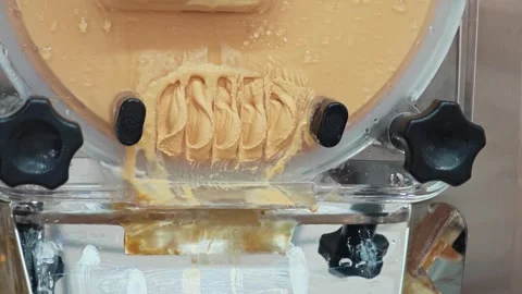 Alternative view of fresh Thai tea gelato ice cream dispensing from a machine. Vídeos de archivo 347633026