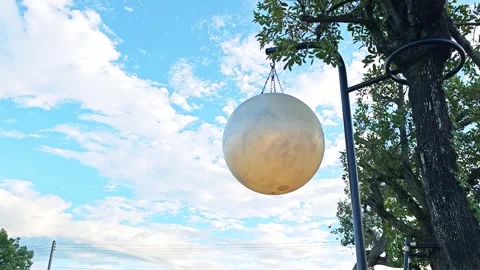 Alternative view of a giant metallic sphere hanging against a cloudy blue sky. Stock Footage 347457245