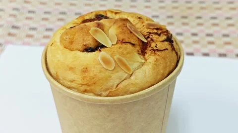 Alternative view of a round raisin bread with almond flakes in a paper cup. Stock Footage 345815908