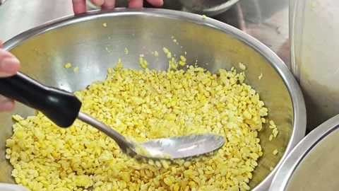 Alternative view of scooping steamed yellow split mung beans with a metal ladle. Stock Footage 346605634