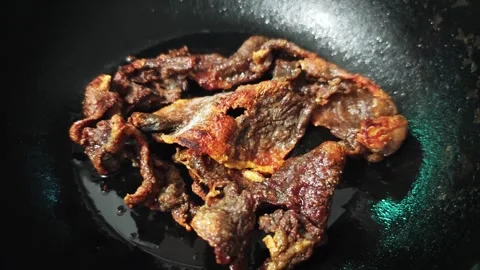 Alternative view of Thai deep-fried sun-dried beef in a black iron wok. Stock Footage 347633095