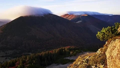 Altocumulus cloud forming over the wrinkle of a mountain ridge, illuminated at Stock-Footage 255311275