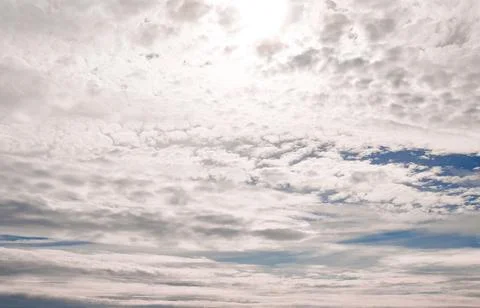 Altocumulus clouds drift through a blue sky, dense cloudscape merging into .. Fotos de archivo