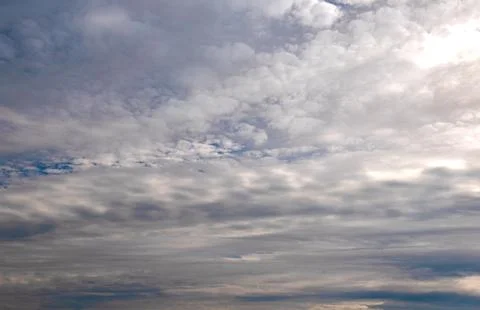 Altocumulus clouds layer a blue sky, soft cloudscape drifting into an overc.. Fotos de archivo