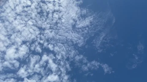 Altocumulus clouds scattered across a bright blue clear sky. 4K Stock Footage 343451864