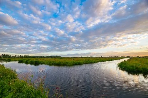 Altocumulus sheep clouds over water-filled ditches and grasslands in the country Stock Photos