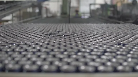 Aluminum Beer Cans / Soda Cans travel down an Assembly Line on a Factory Floor Stock Footage