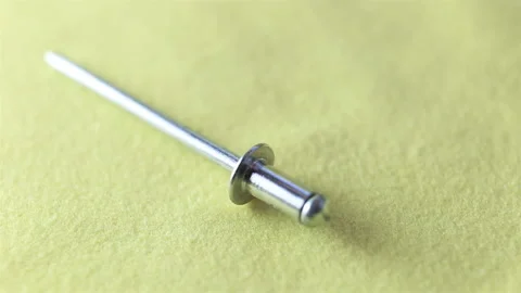Aluminum rivets fall down. Extreme close-up, real time, on a yellow background Stock Footage 129637973