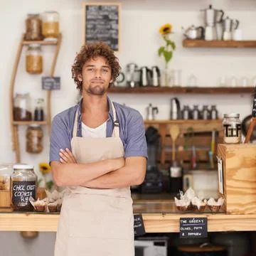 Always a friendly face at the cafe. Portrait of a male barista standing happily Stock Photos