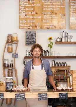 Always a friendly face at the cafe. Portrait of a male barista standing at a Stock Photos