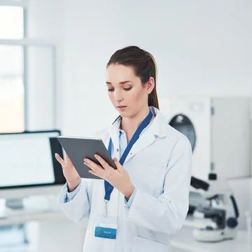 Always keep track of the data. a focused young female scientist browsing on a Stock Photos