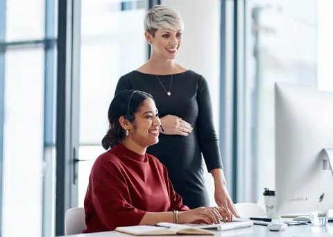 Always there to help each other out. a businesswoman helping a colleague in a Stock Photos