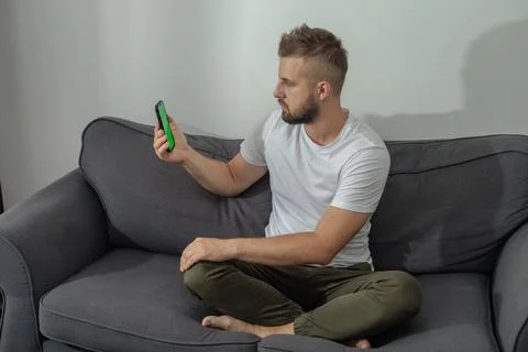Always in touch. Cheerful handsome young man using his smartphone while sitting  Foto stock