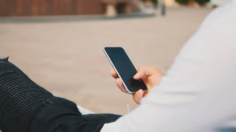 Always in touch. Young man is using smartphone outside, while sitting on the Video stock 124968343