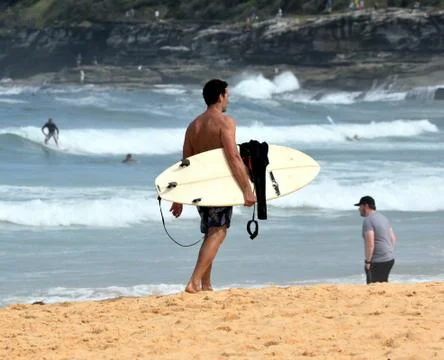 Amateur surfer is walking on the beach with his surfboard Stock Photos