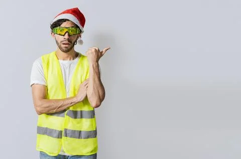 Amazed builder engineer in christmas hat pointing a copy space. Engineer ma.. Stock Photos