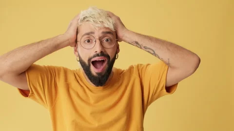 Amazed man looking at camera with big eyes, puts hands on head, isolated on Stock Footage 253934591